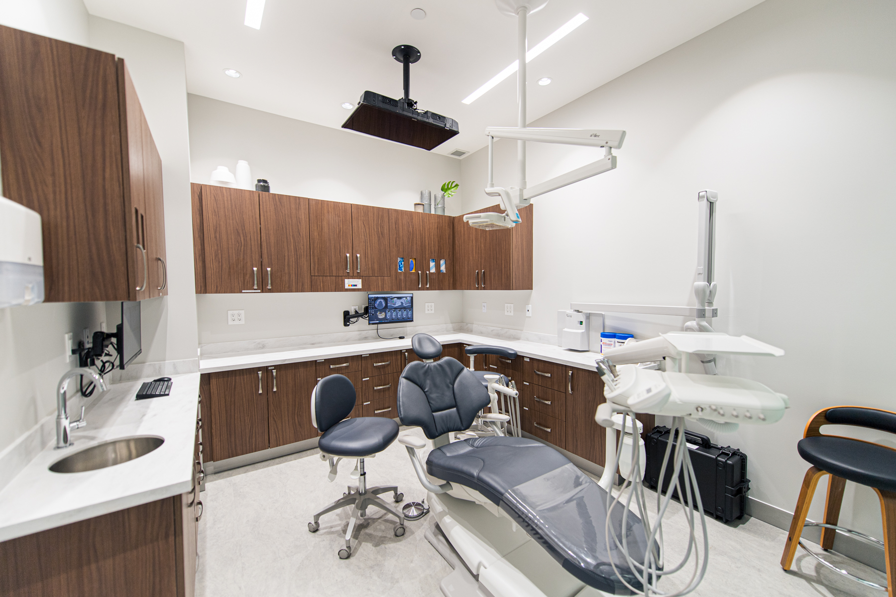 Dental treatment room with cabinetry, clinical equipment, and exam chair